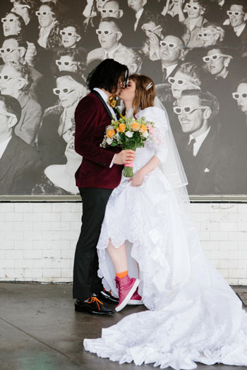 A couple is kissing in front of a poster on the street.