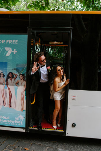 Bride and groom waving bye on the bus