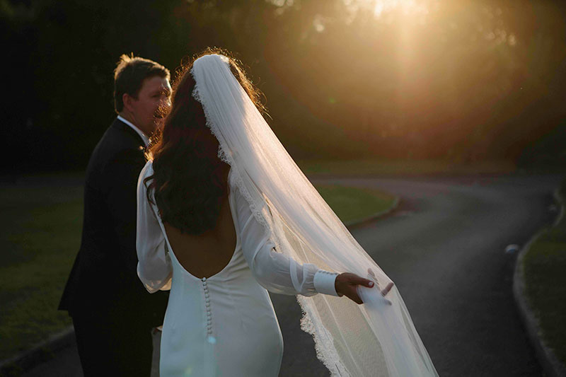 A bride and groom walking during sunset.