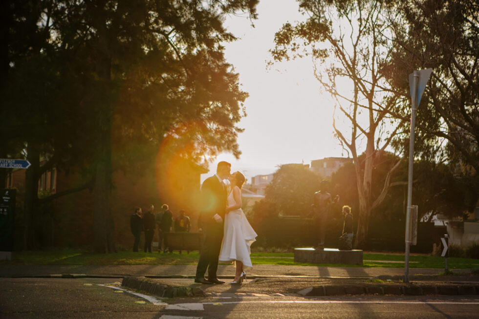 The newlywed couple embraced in a romantic kiss as the sun set in the background.