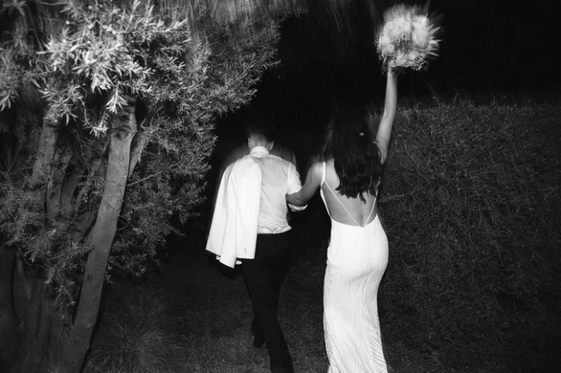 The bride and groom are walking with a bouquet in their hands.