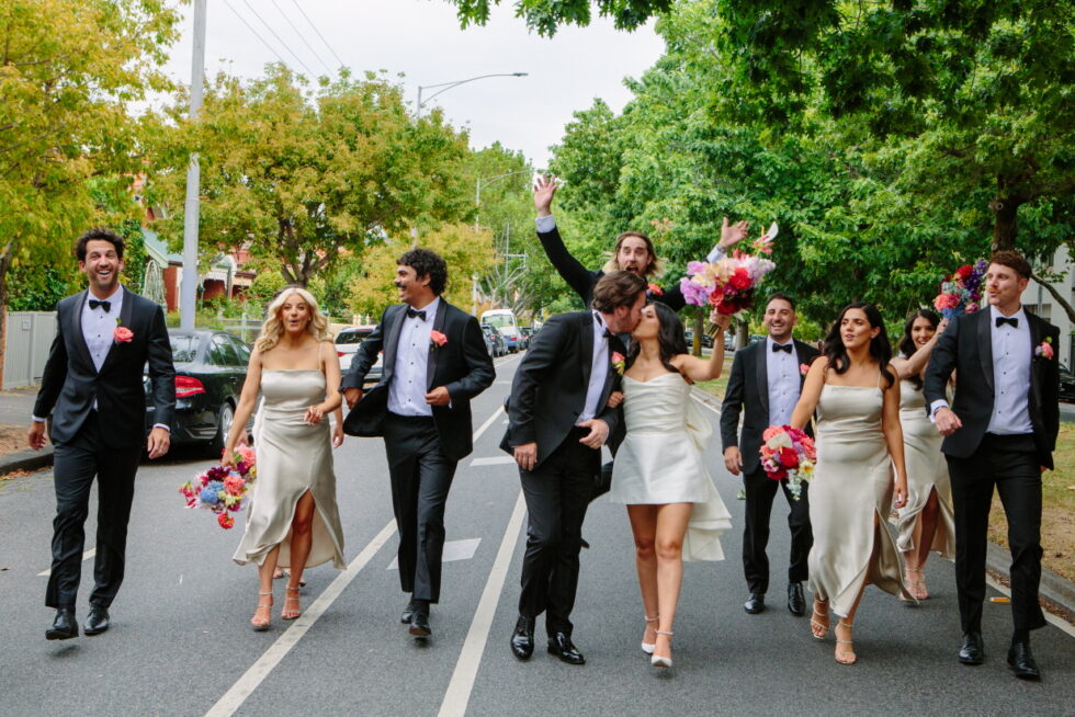 The bride, groom, and their friends are walking on the street.