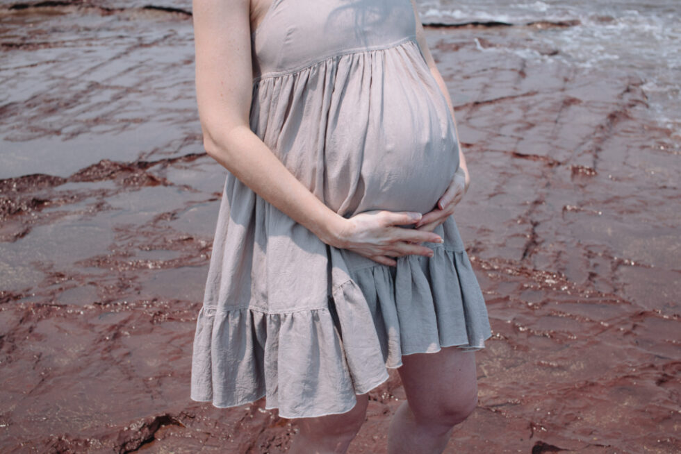 A soon-to-be mother is cradling her belly with her hands.