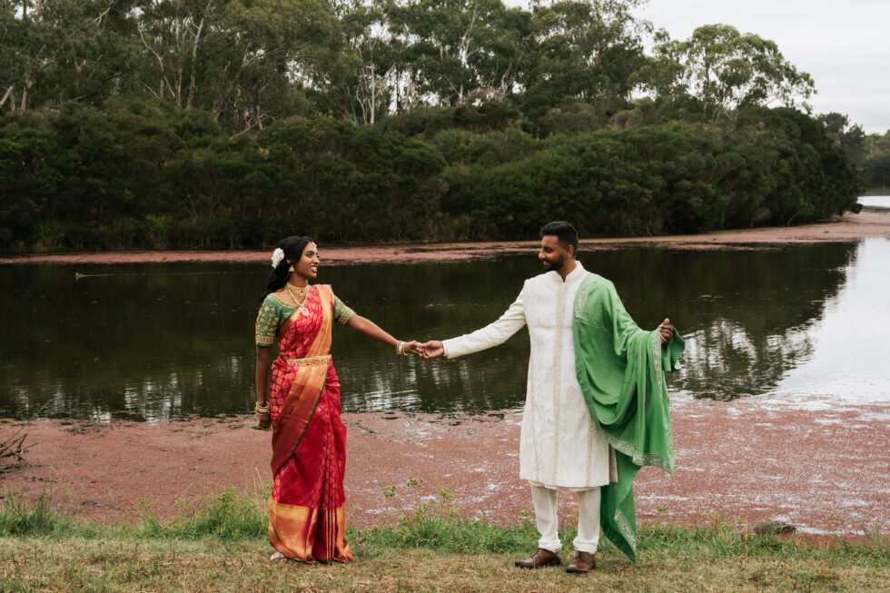 The bride and groom are gazing at each other by the lake.