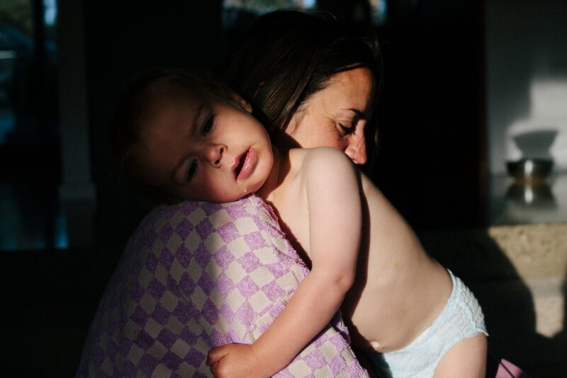 A mother is shown in profile, holding her baby.