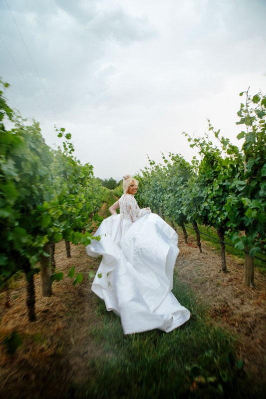 The bride is running in the winery field.