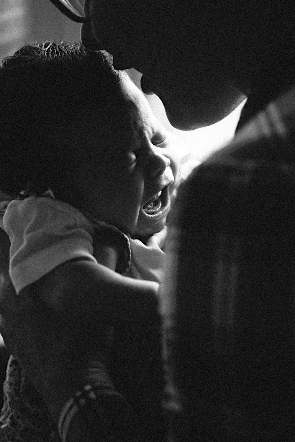Black and white photo of a person holding a baby in their hands.