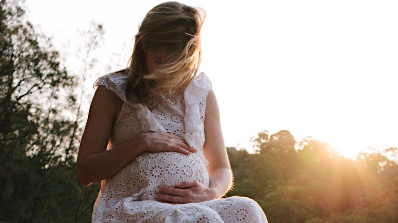 Pregnant woman holding her belly outside in nature.